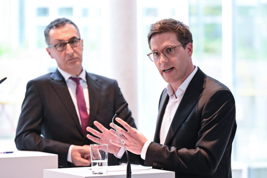 Zwei Männer im Anzug sprechen bei einer Konferenz.