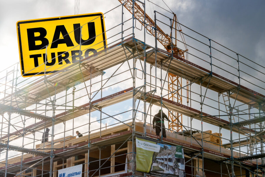 Gerüst und Bauarbeiter auf Baustelle mit gelbem Schild "BAU TURBO".