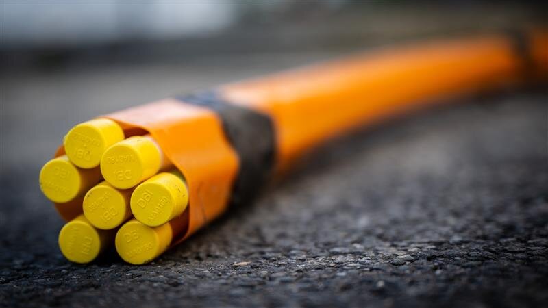 Orange Kabelbündel mit gelben Enden auf Asphalt.