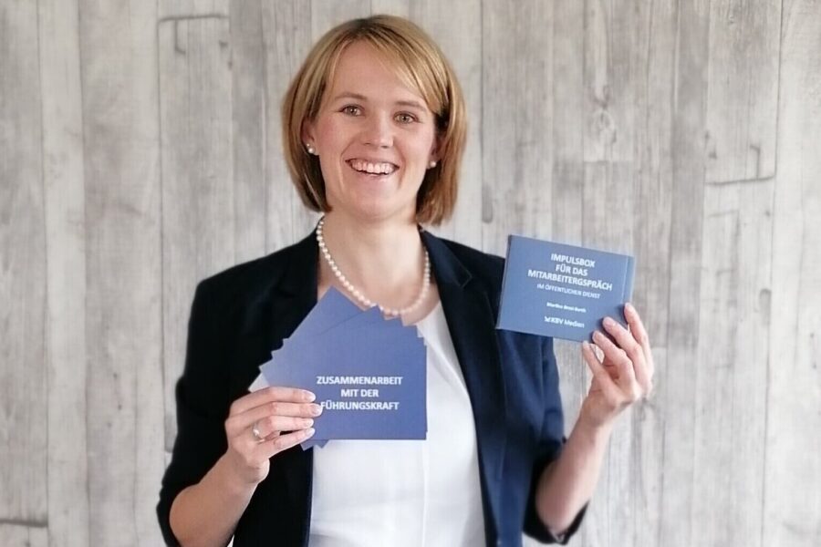 Person mit Karteikarten in Blau, Text: "ZUSAMMENARBEIT MIT DER FÜHRUNGSKRAFT".