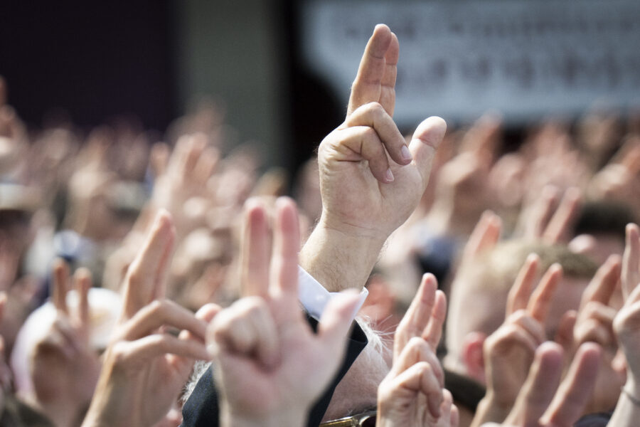 Viele erhobene Hände mit ausgestreckten Fingern in einer Menschenmenge.