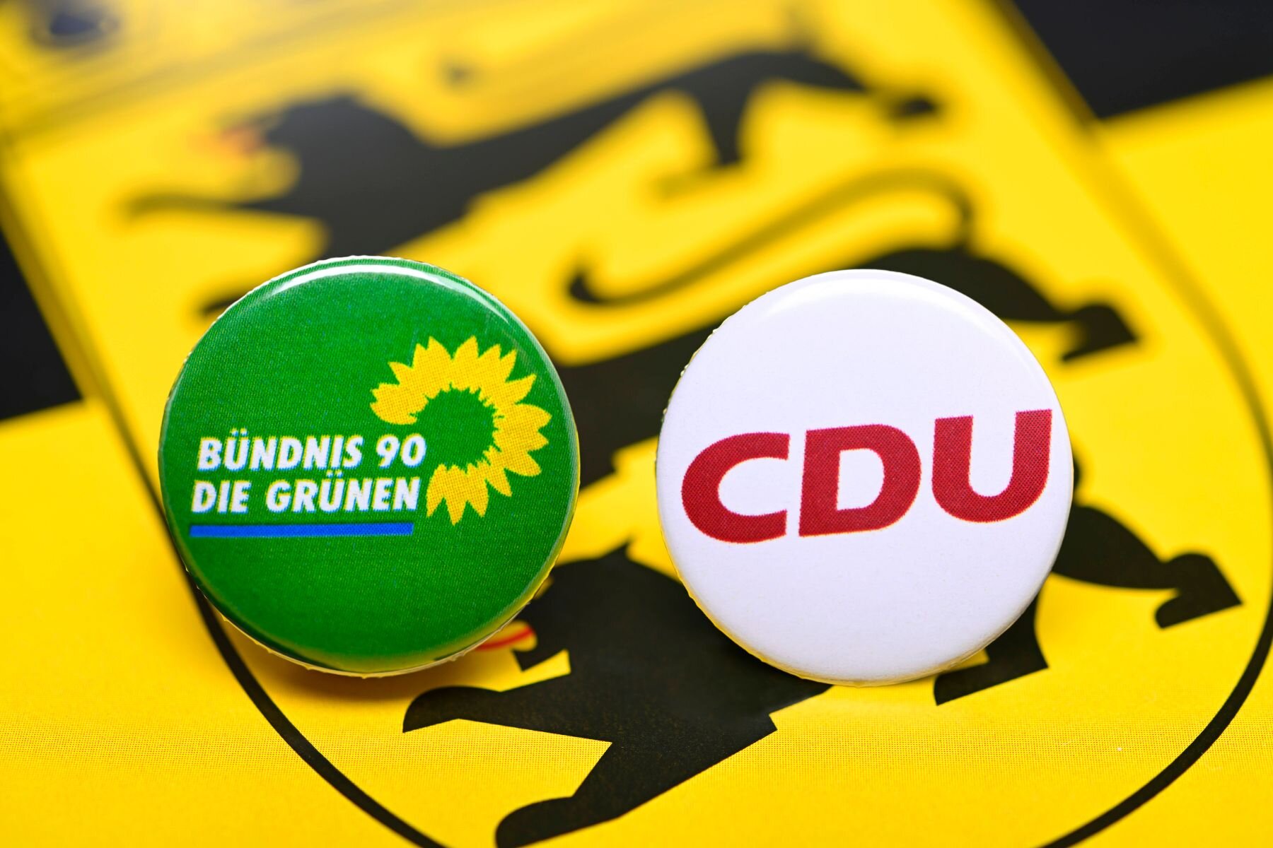 Zwei Buttons: "BÜNDNIS 90/DIE GRÜNEN" und "CDU", vor gelbem Hintergrund.