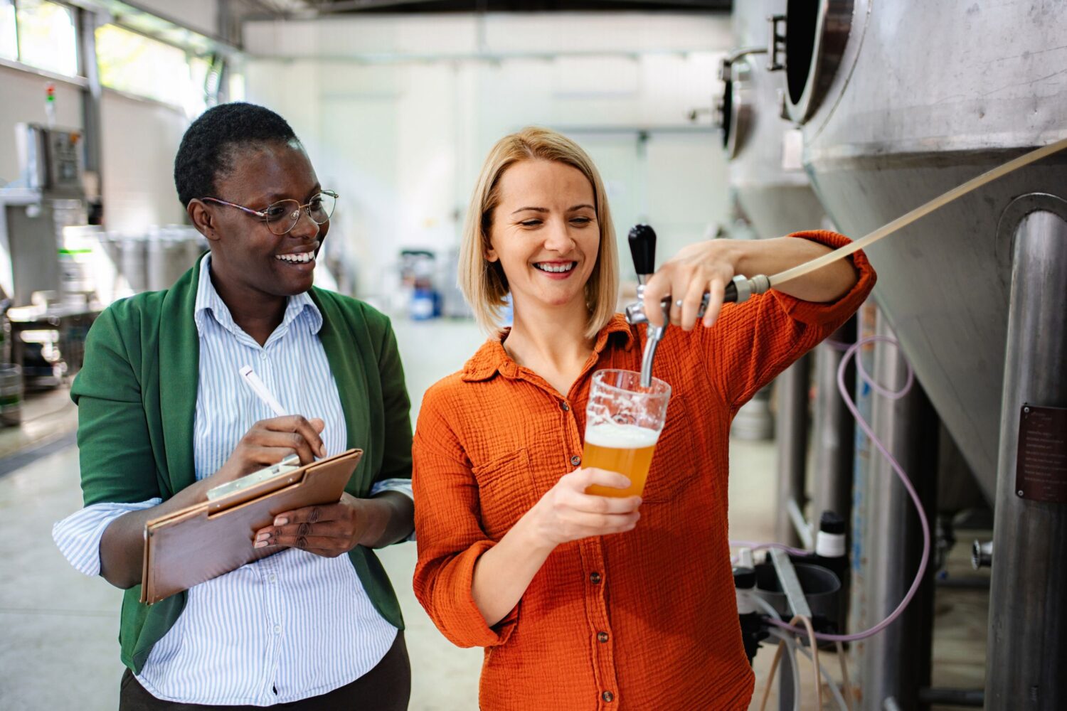 Zwei Personen in einer Brauerei, eine zapft Bier, die andere schreibt auf.