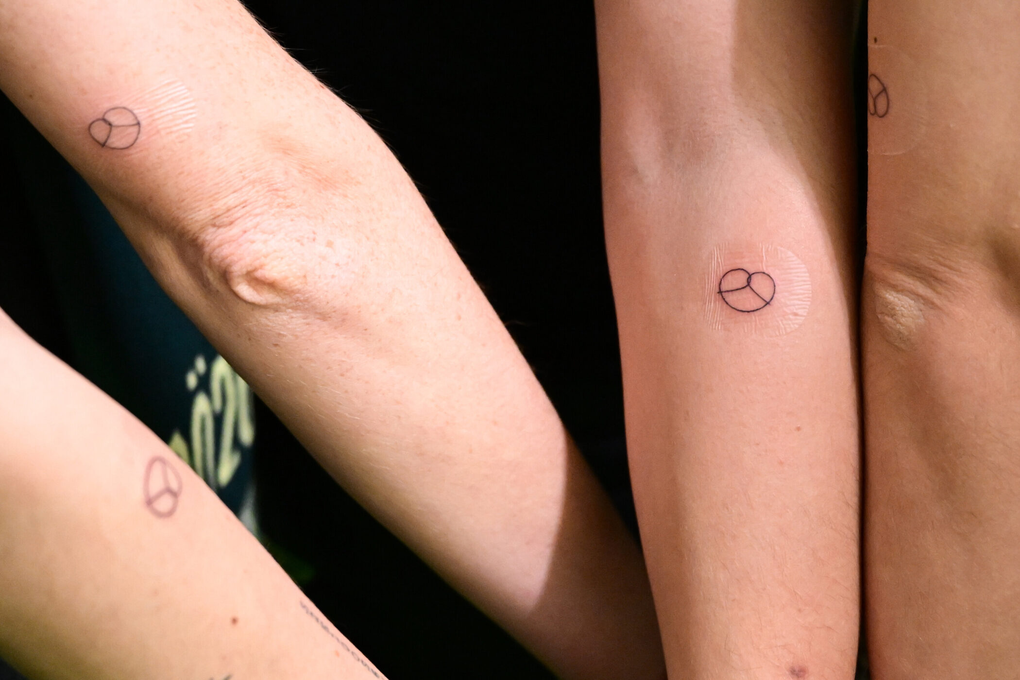 Drei Arme mit kleinen Kreismotiven auf der Haut.