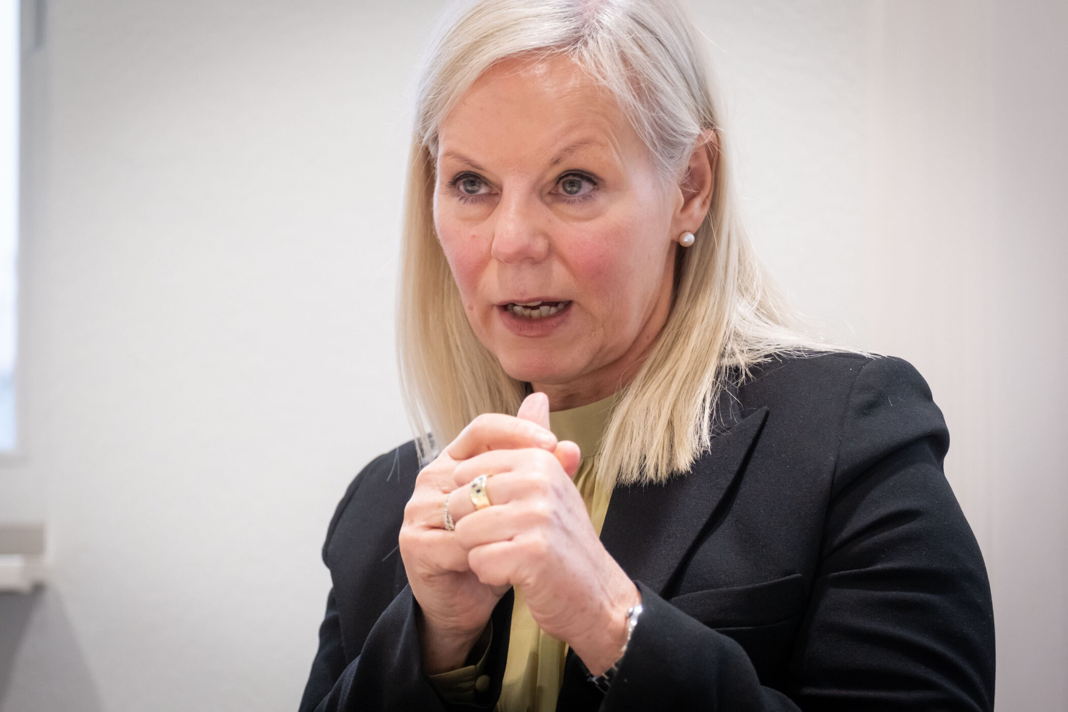 Frau mit langen, blonden Haaren spricht und gestikuliert mit den Händen.