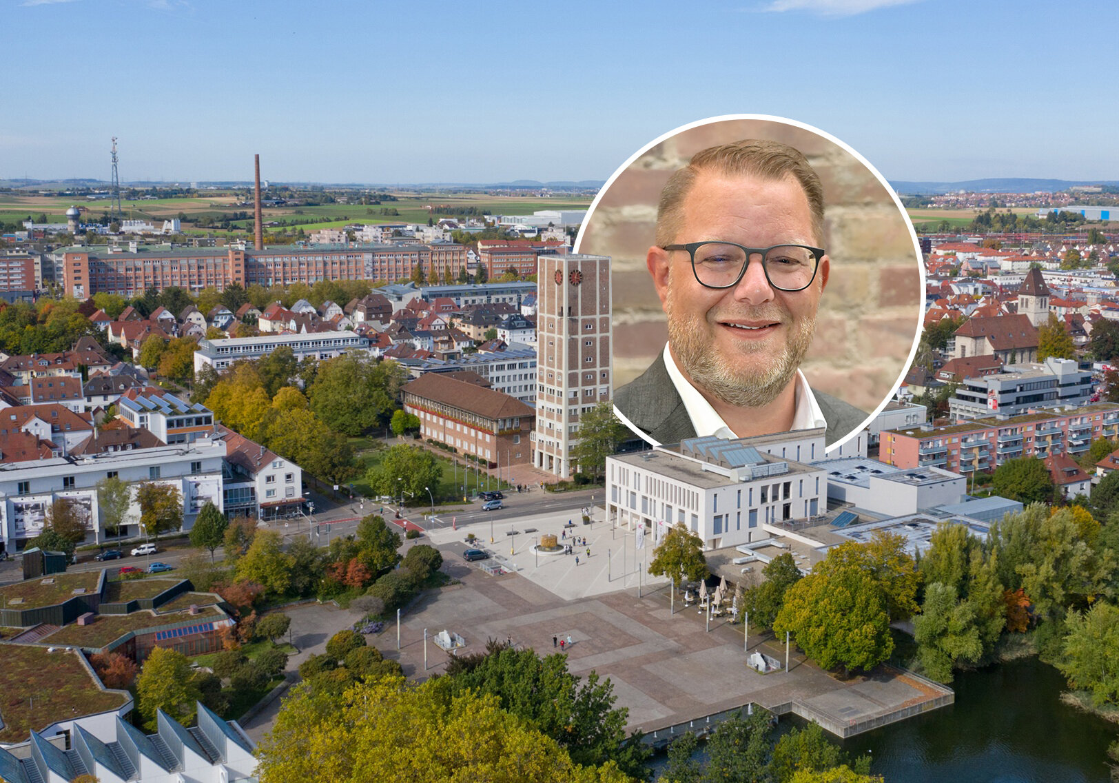 Luftbild einer Stadt mit einem Rathaus und eingekreistes Porträt eines Mannes.