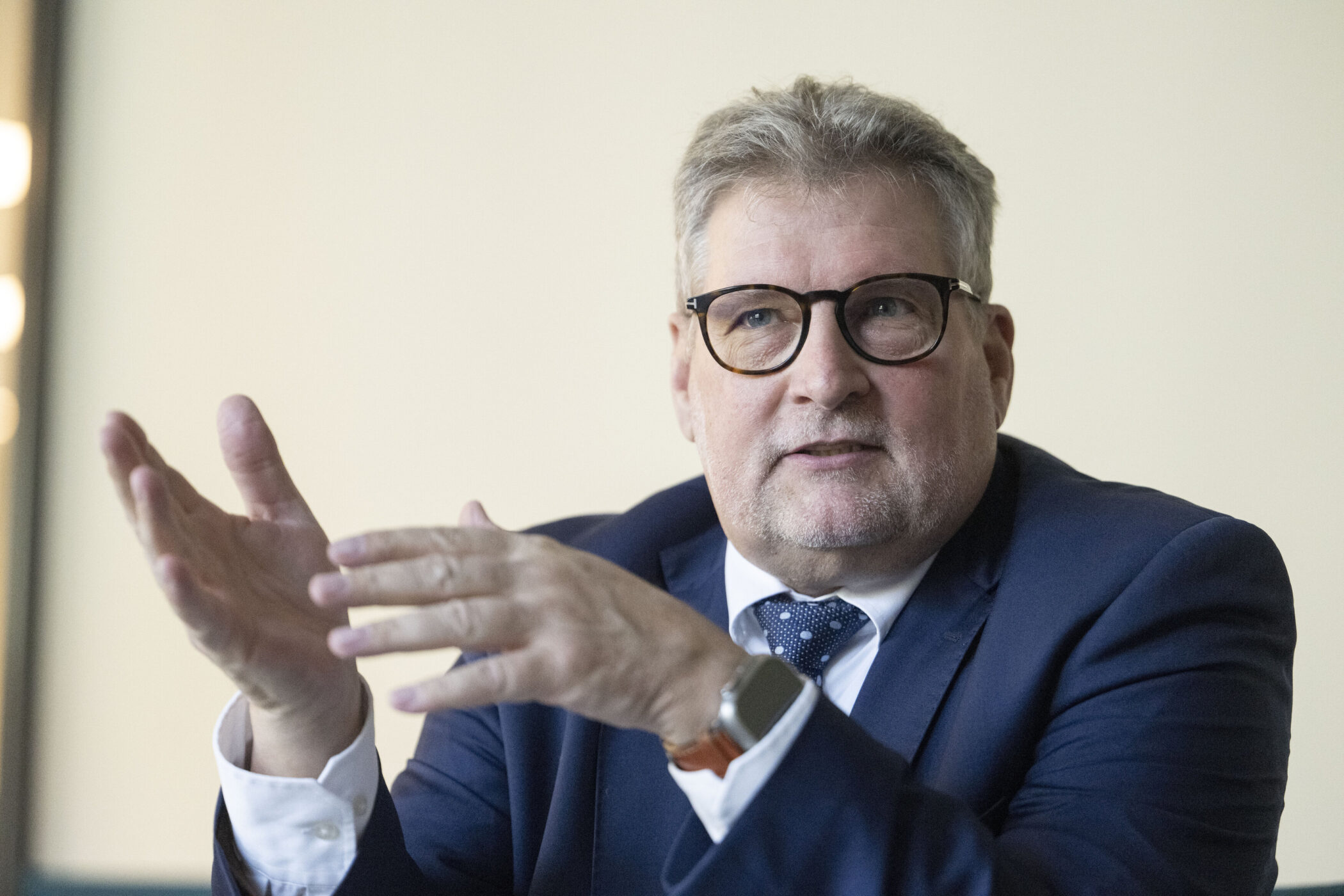 Ein Mann in einem Anzug gestikuliert mit den Händen.