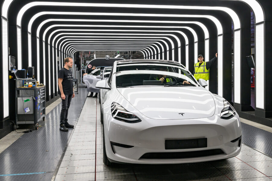 Drei Personen bei der Inspektion eines weißen Autos in einem beleuchteten Tunnel.