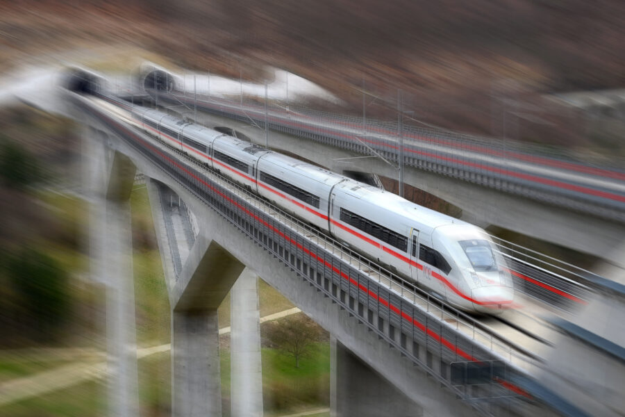 Ein weißer Hochgeschwindigkeitszug auf einer hohen Brücke.