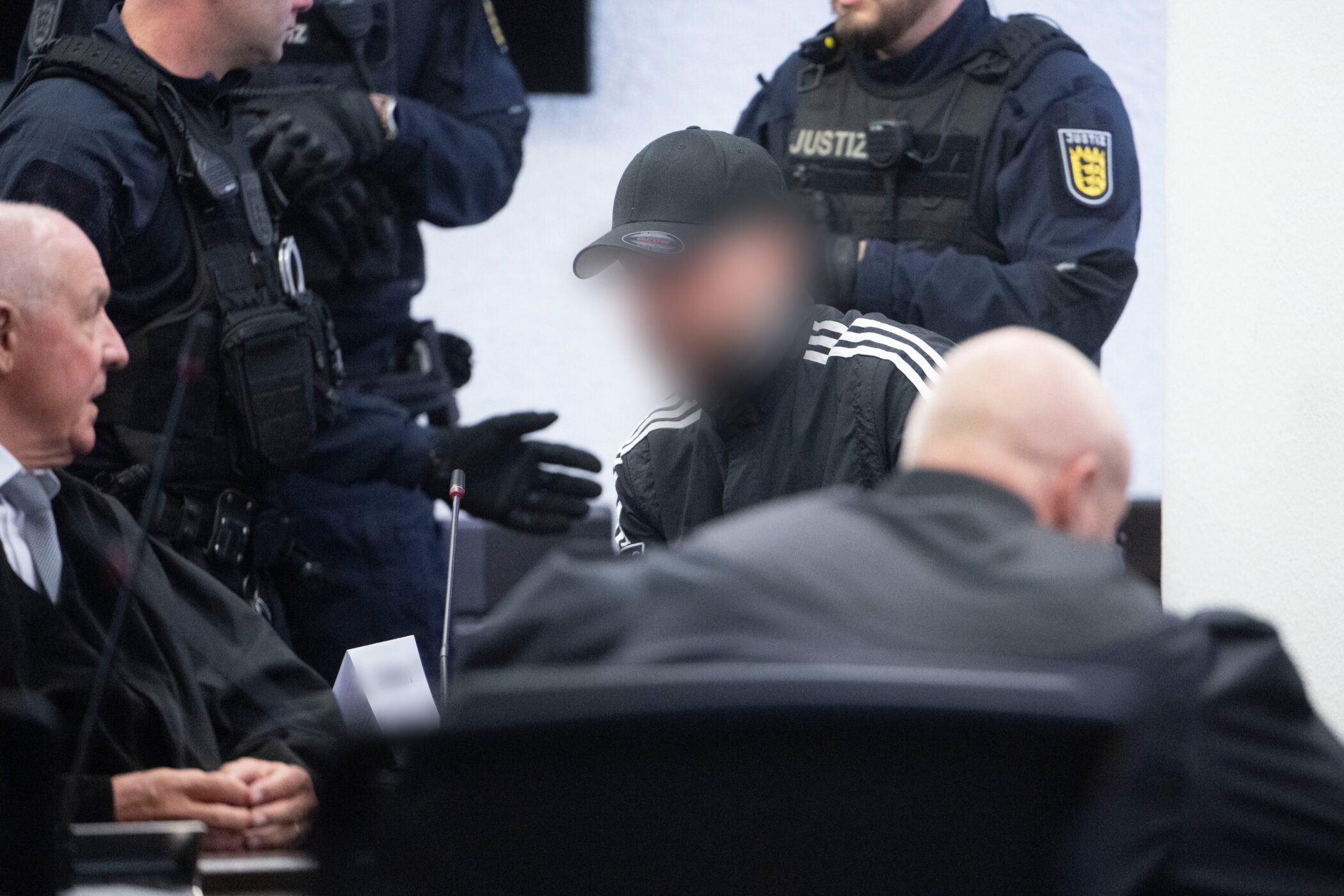 Mehrere Personen in einem Raum, eine trägt Justiz-Uniform.