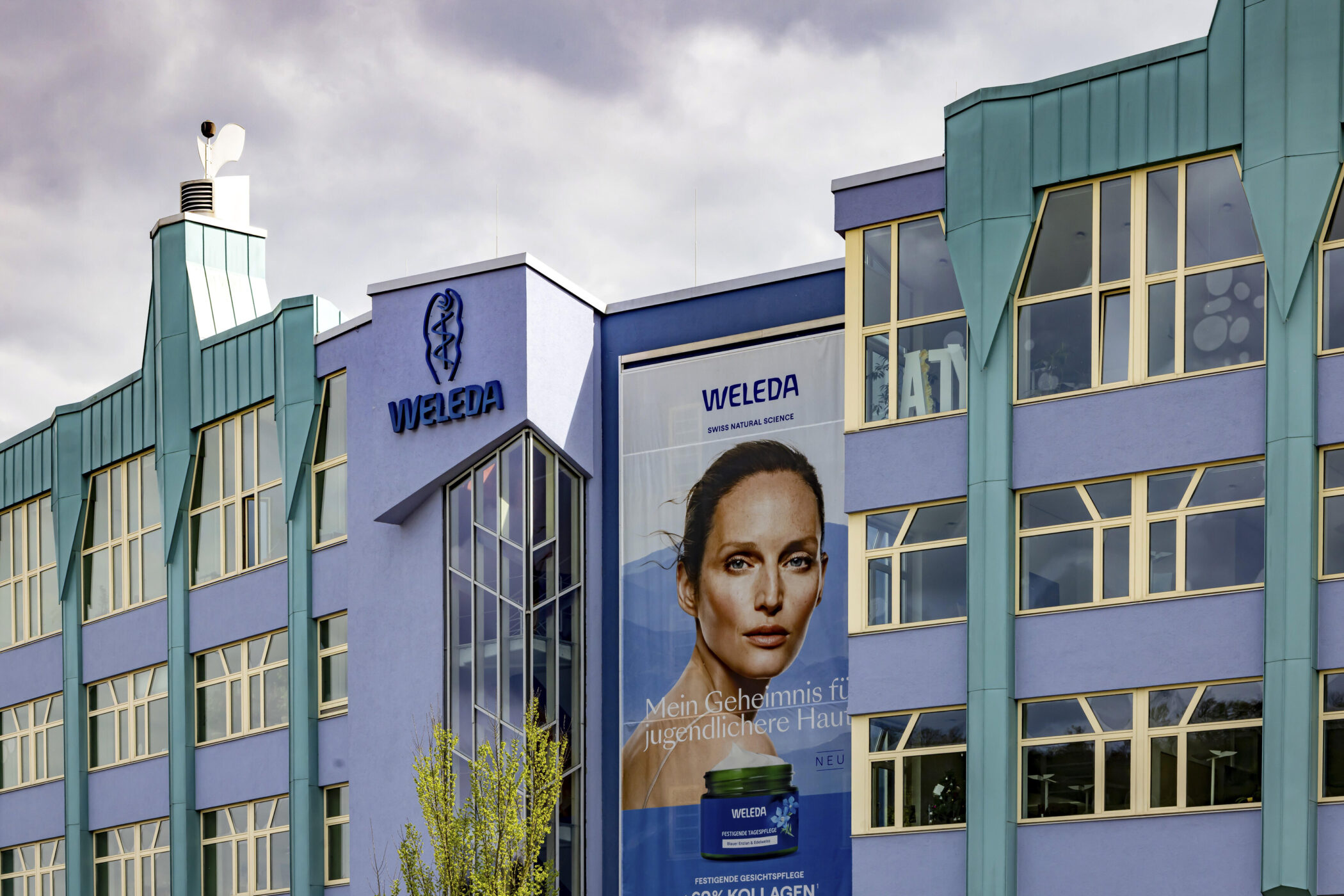 Gebäude mit Weleda-Logo, großes Werbeplakat.