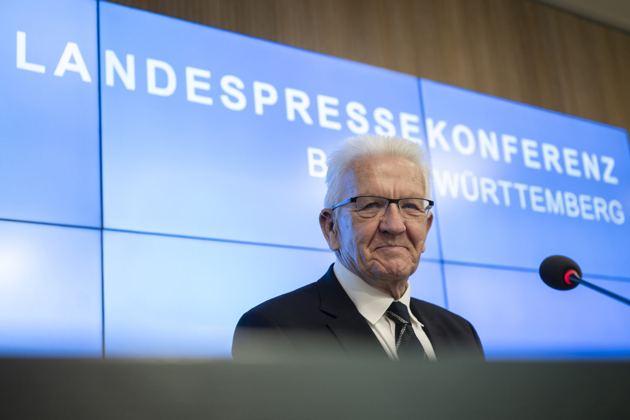 Ein Mann vor einem Mikrofon, Hintergrundtext: "Landespressekonferenz".