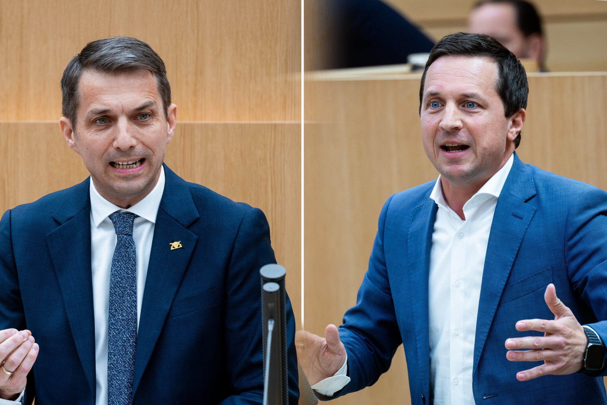 Zwei Männer in blauen Anzügen sprechen gestikulierend in einem Raum.
