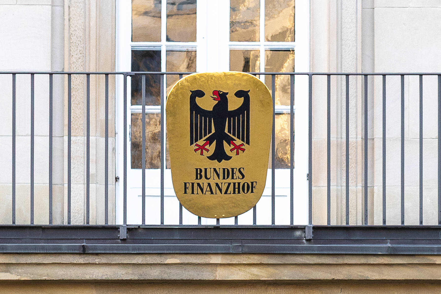 Schild mit Bundesadler und Text "Bundesfinanzhof" an einem Gebäude.