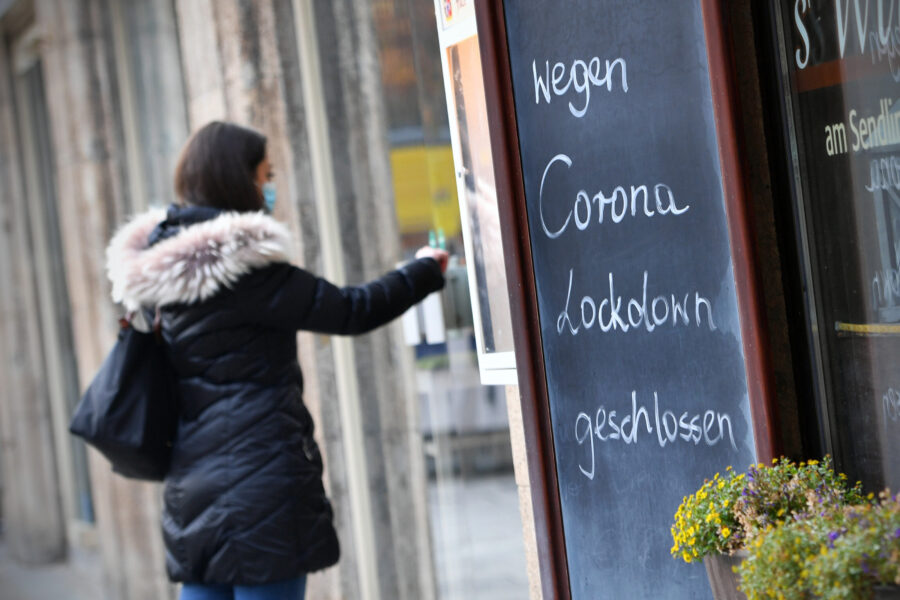 Eine Person mit Maske vor Schild: „Wegen Corona Lockdown geschlossen“.