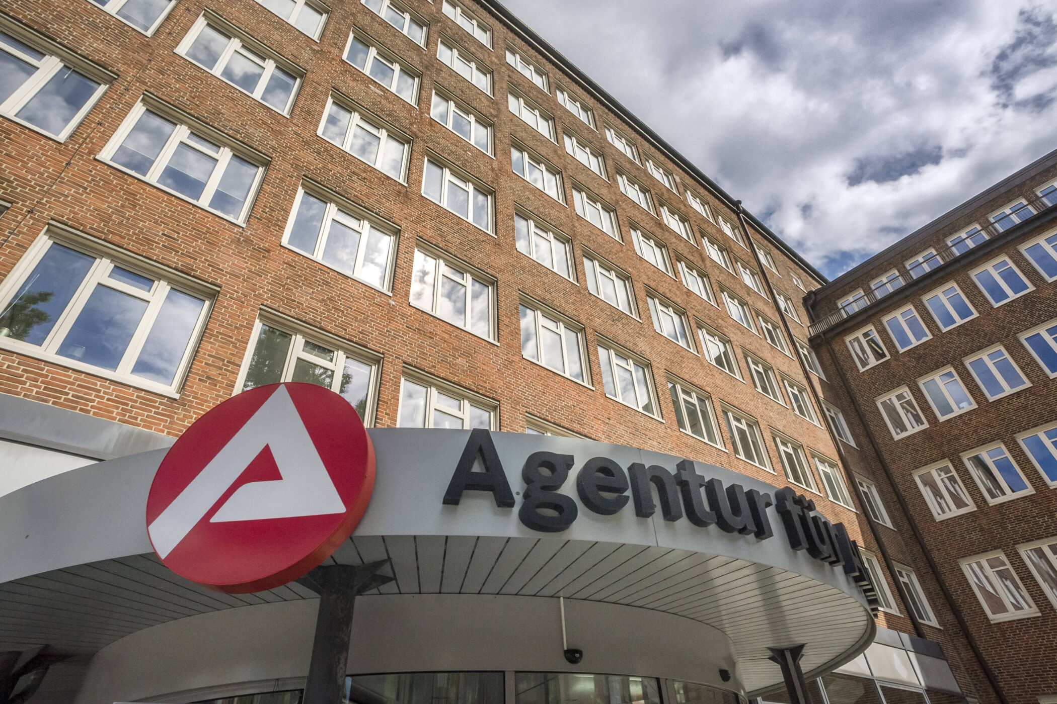 Backsteingebäude, Agentur-Logo und teilweise sichtbarer Schriftzug "Agentur fü".
