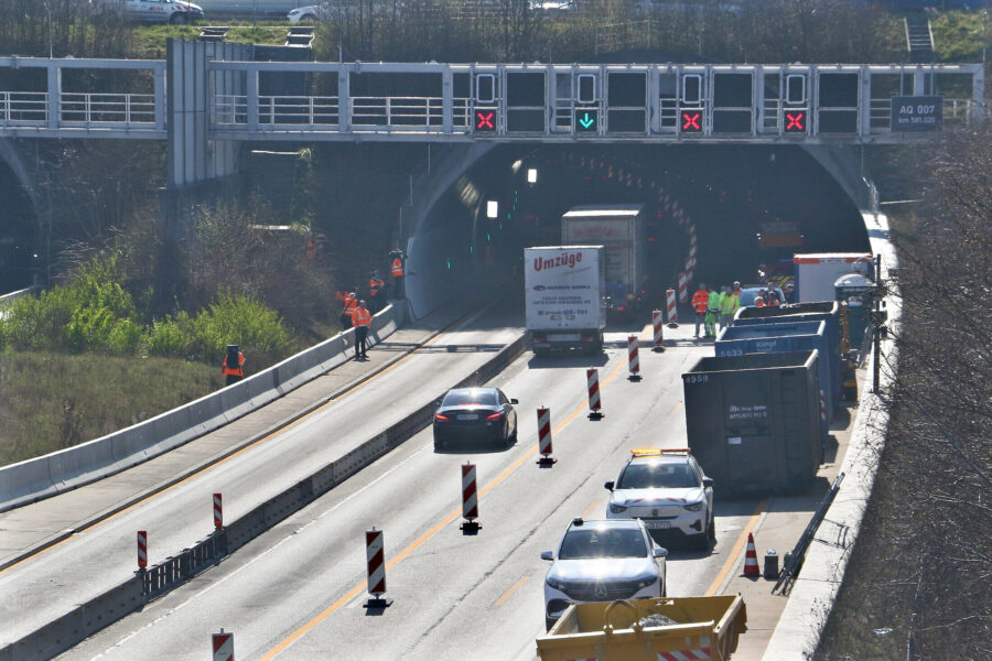 Tunnelbaustelle mit mehreren Fahrzeugen und Menschen in Warnwesten. Verkehrsabsperrung.