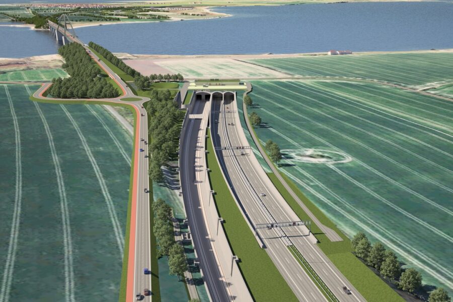 Straße führt durch Tunnel, daneben Brücke über Fluss, umgeben von Feldern und Bäumen.