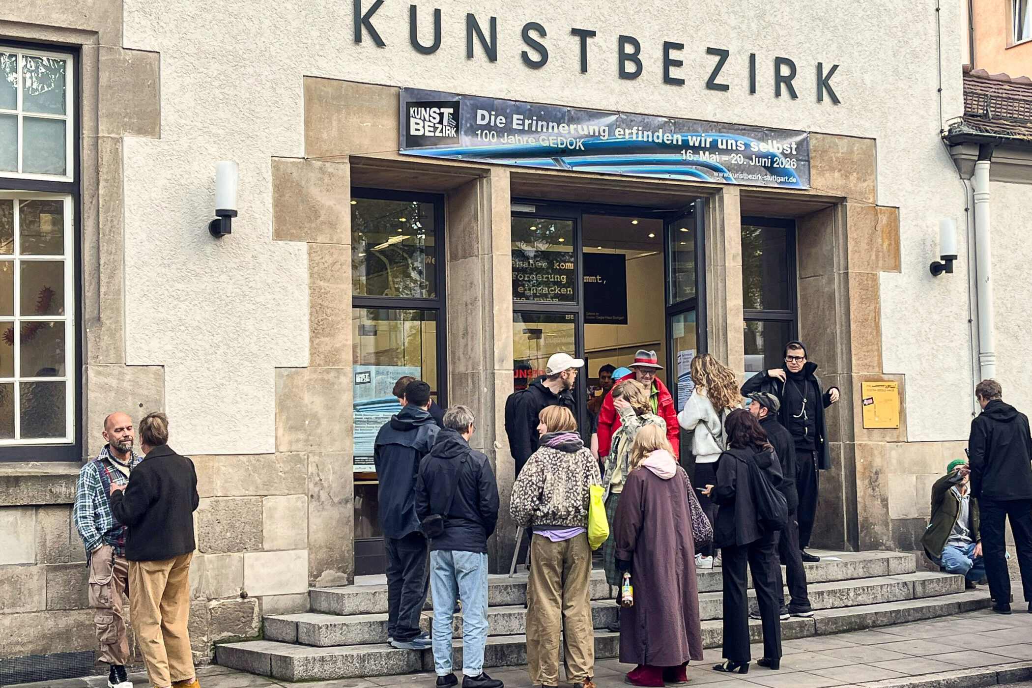 Mehrere Personen vor dem Eingang eines Gebäudes mit der Aufschrift "KUNSTBEZIRK".