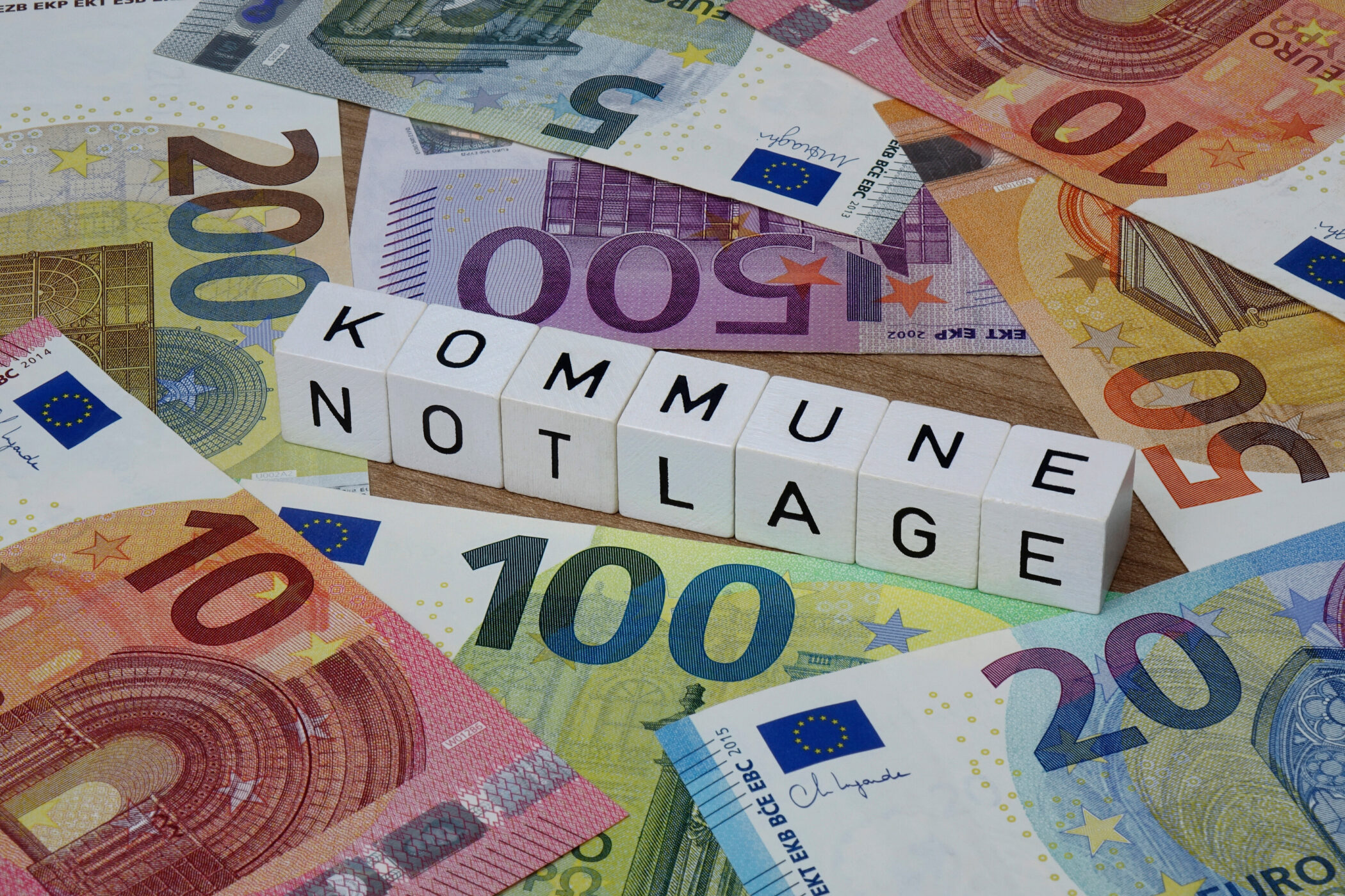 Euroscheine und Würfel mit dem Text "KOMMUNE NOTLAGE".