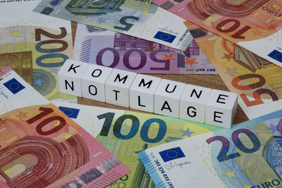 Euroscheine und Würfel mit dem Text "KOMMUNE NOTLAGE".