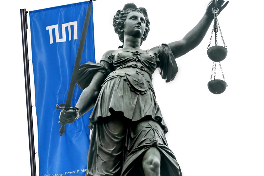 Statue mit Schwert und Waage, daneben eine blaue Flagge mit TUM-Logo.
