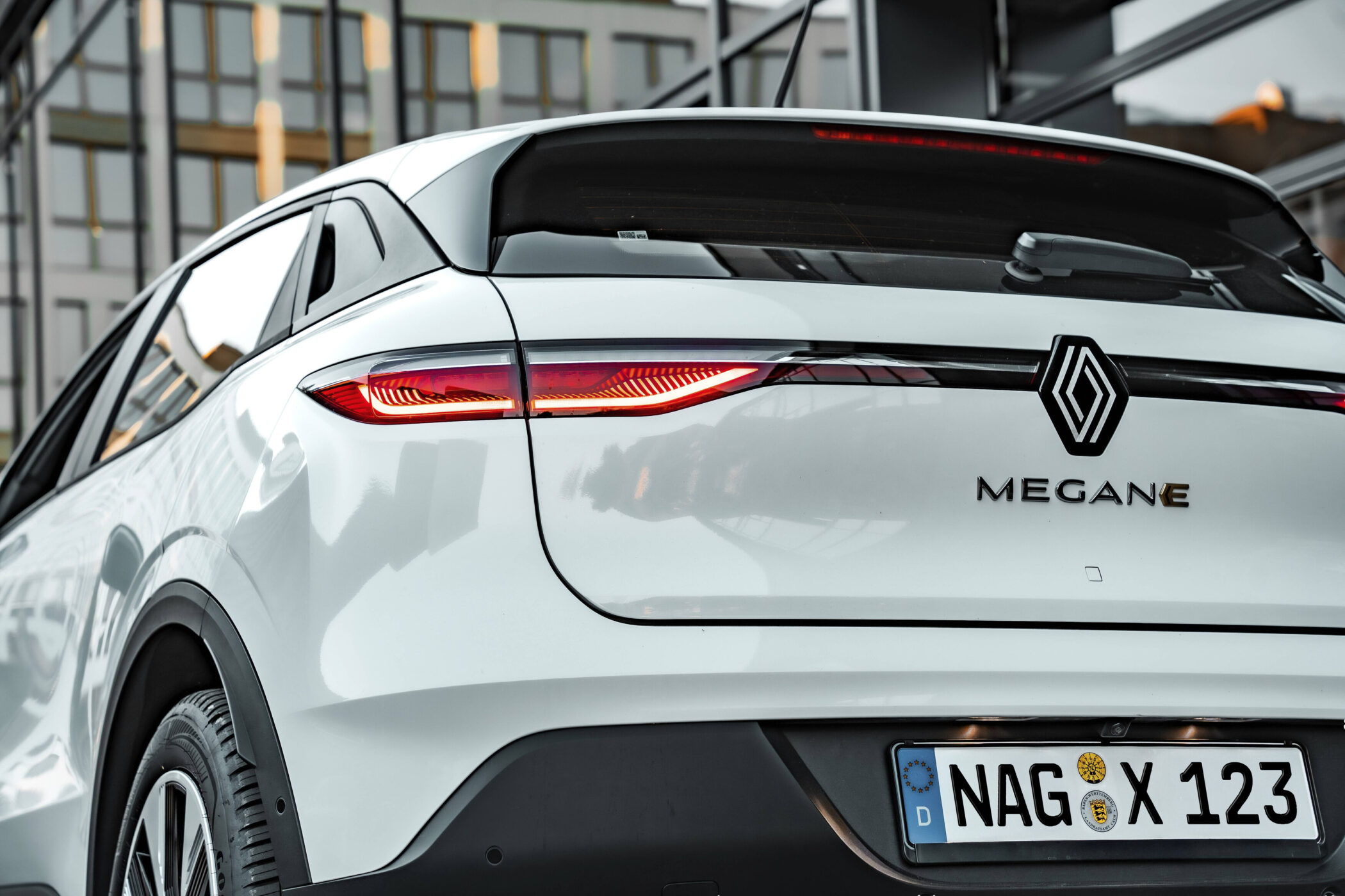 Weißes Auto von hinten, Markenlogo, „MEGANE“, Nummernschild „NAG X 123“.