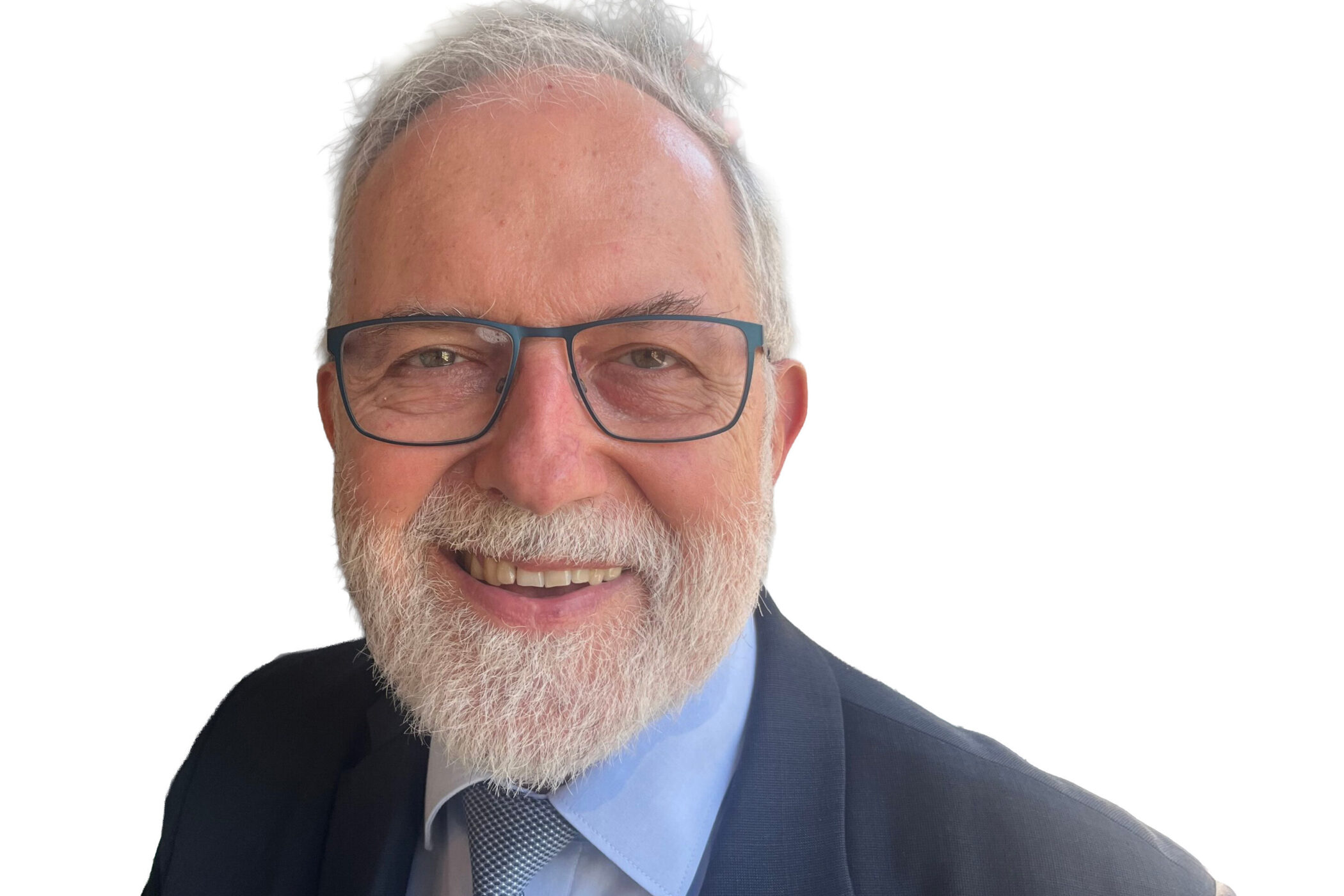 Älterer Mann mit Brille, Bart, Anzug und Krawatte, lächelnd vor weißem Hintergrund.