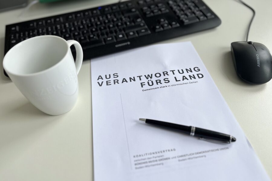 Computertastatur, Maus, Tasse, Dokument mit Stift auf einem Tisch.
