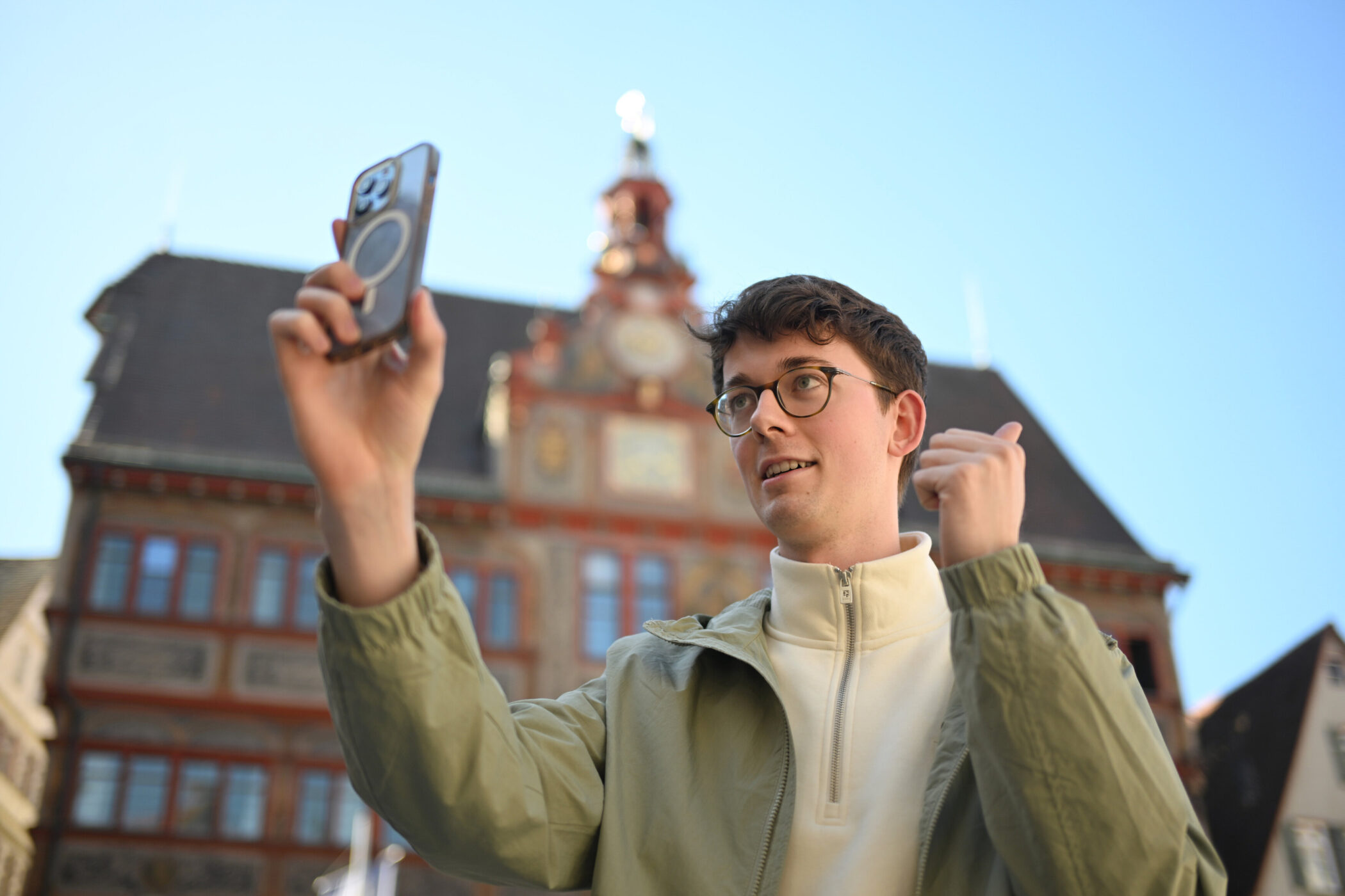 Eine Person macht ein Selbstporträt vor einem historischen Gebäude.