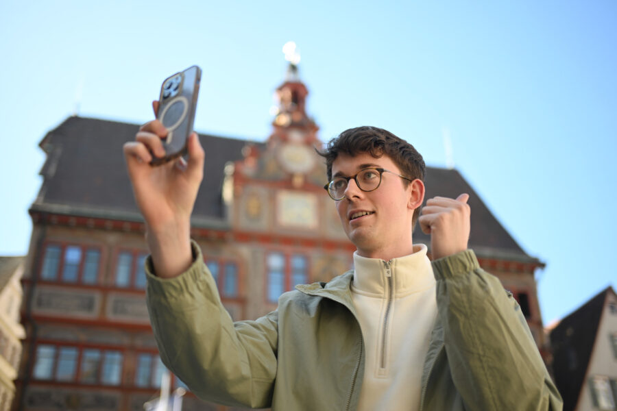 Eine Person macht ein Selbstporträt vor einem historischen Gebäude.