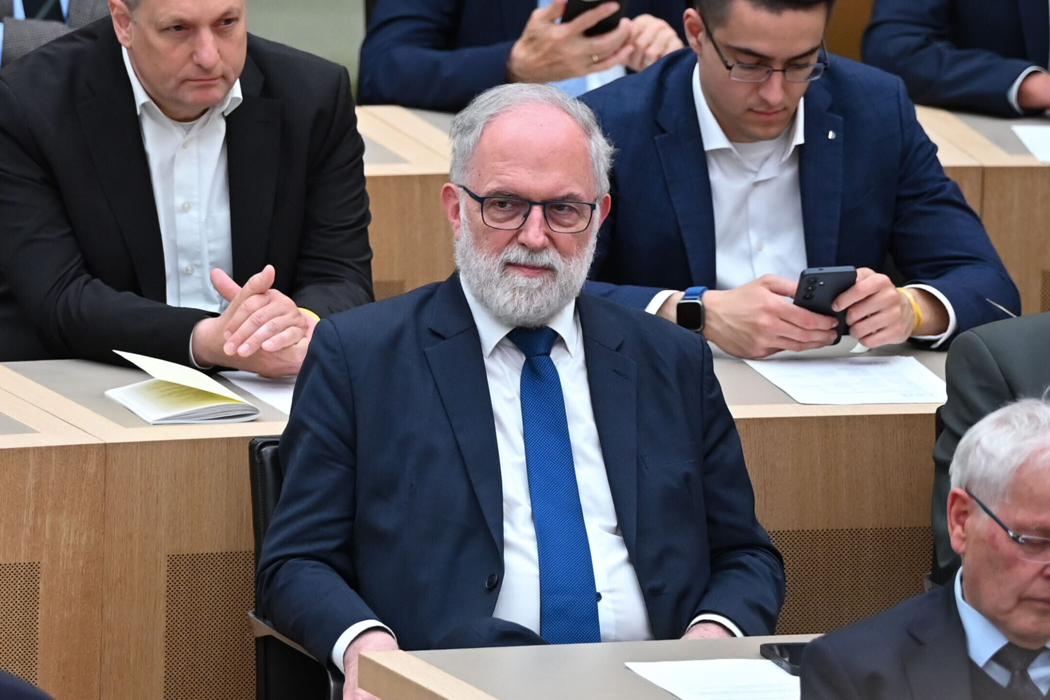 Mehrere Männer in Anzügen sitzen in einem Konferenzsaal.