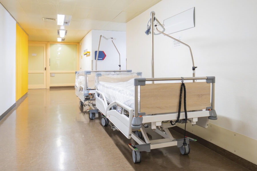 Krankenhausflur mit zwei leeren Betten nebeneinander an der Wand.