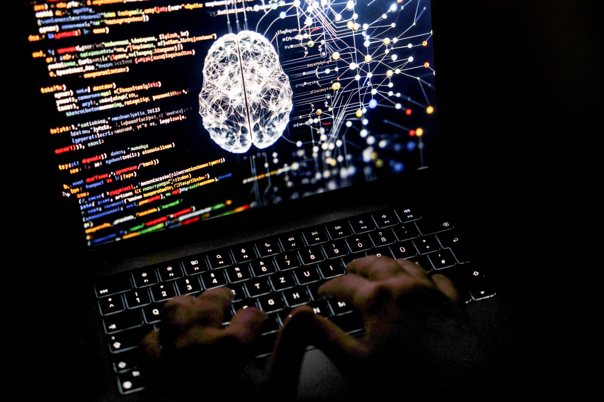 Hände tippen auf Laptop-Tastatur, auf dem Display Code und neuronales Netz.