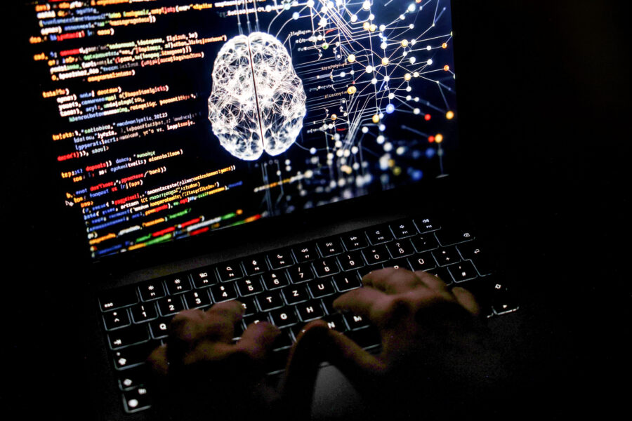 Hände tippen auf Laptop-Tastatur, auf dem Display Code und neuronales Netz.