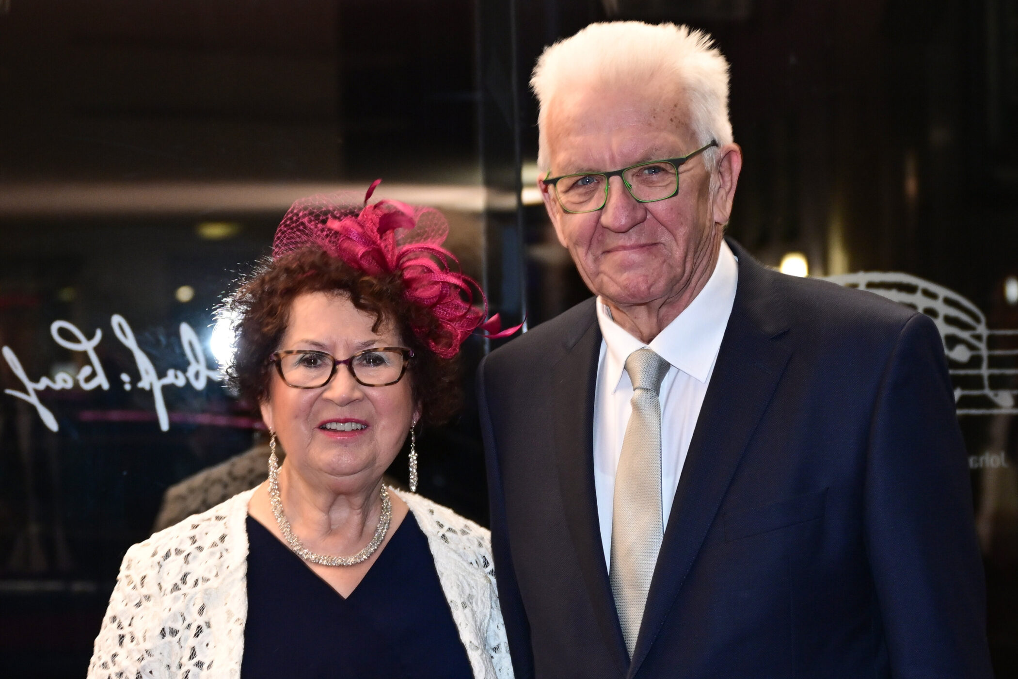 Ein Mann und eine Frau lächelnd, die Frau trägt einen roten Hut.