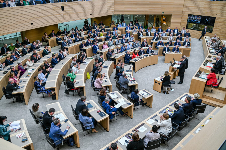 Menschen in einem halbrunden Saal bei einer Versammlung oder Sitzung.