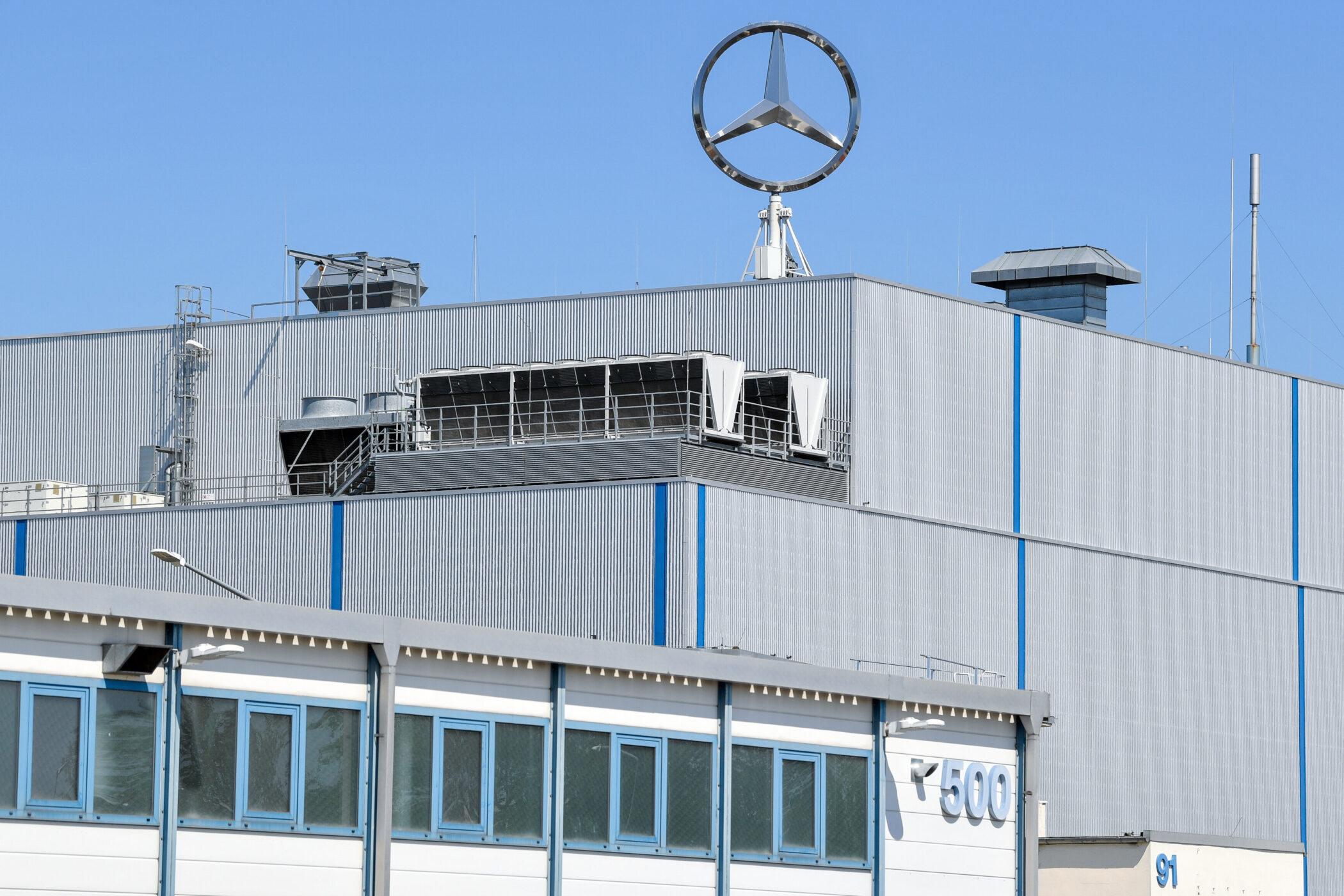 Graues Gebäude mit großem Mercedes-Logo oben, blaue Fenster, Nummer 500 sichtbar.