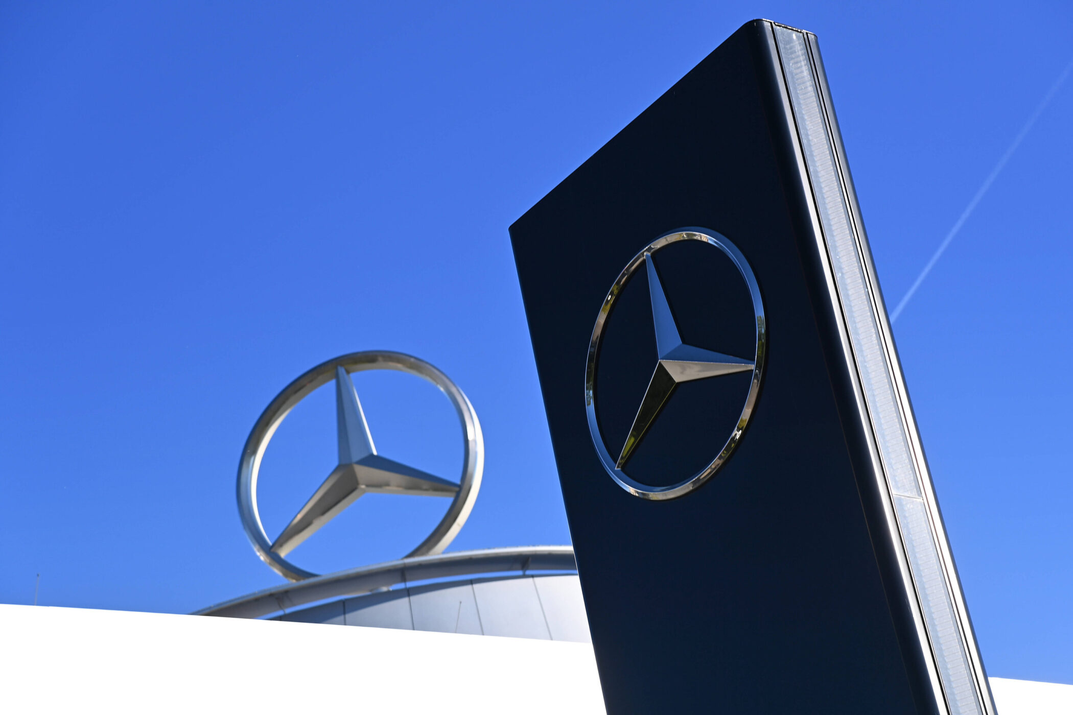 Zwei Mercedes-Logos vor einem blauen Himmel.