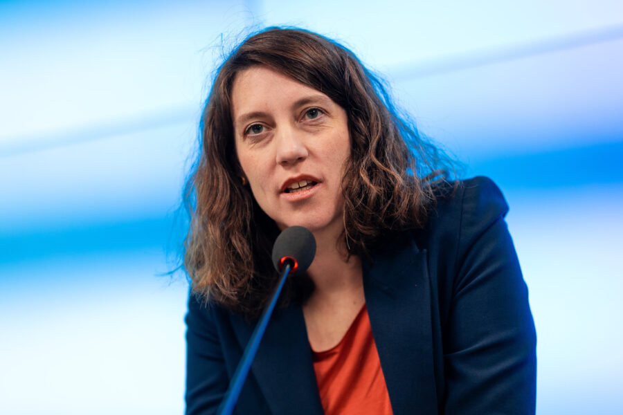 Eine Person spricht in ein Mikrofon vor blauem Hintergrund.