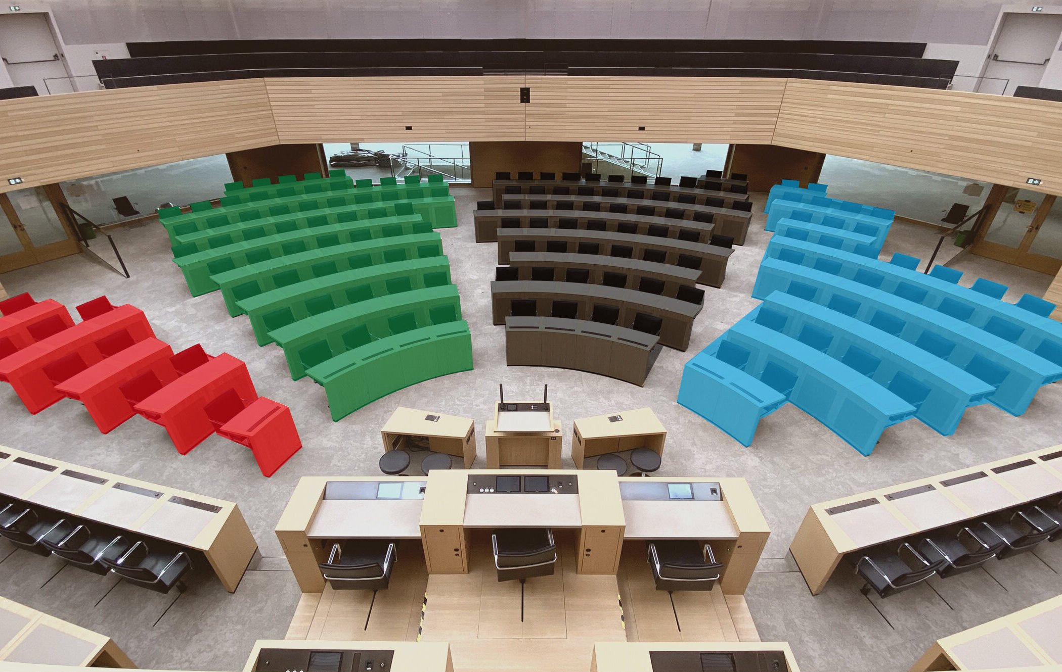 Holzkabinen und bunte Sitzreihen in einem Saal ohne Personen.