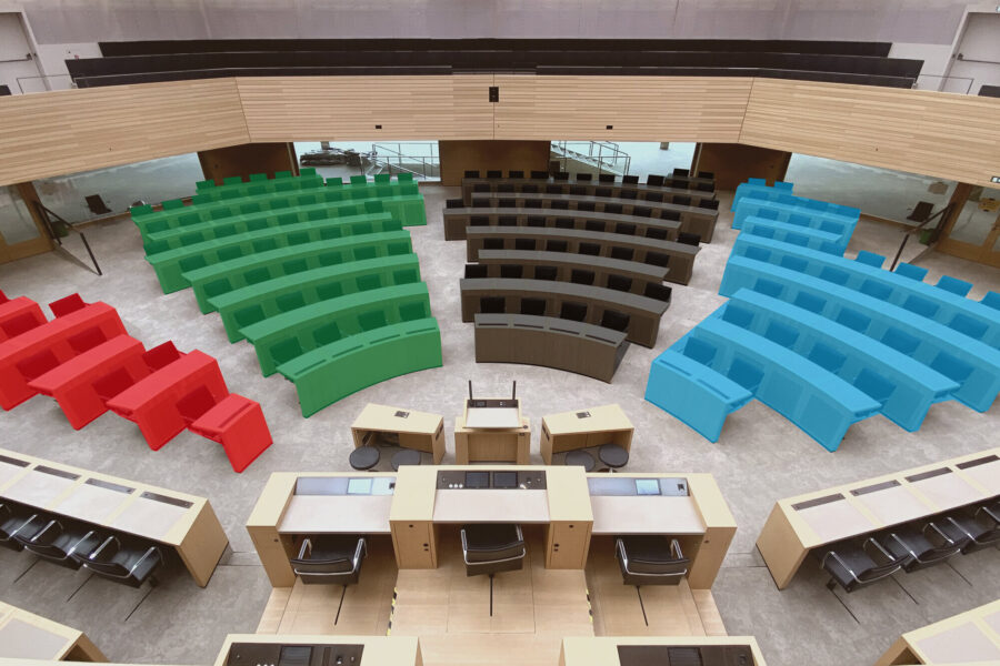 Holzkabinen und bunte Sitzreihen in einem Saal ohne Personen.