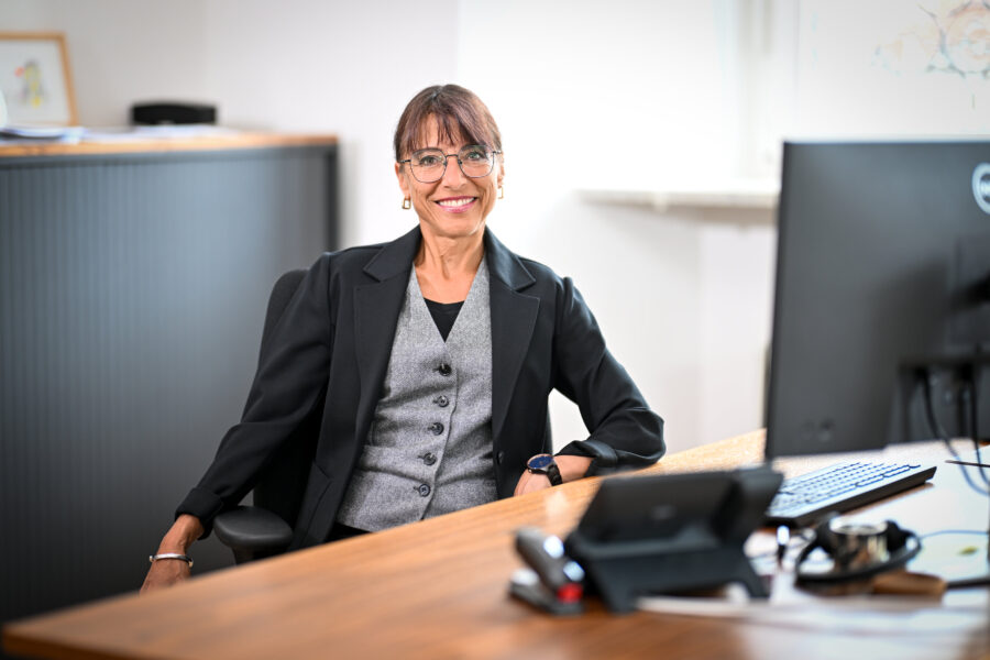 Person an Schreibtisch mit Computerbildschirm und Holzoberfläche im Büro.