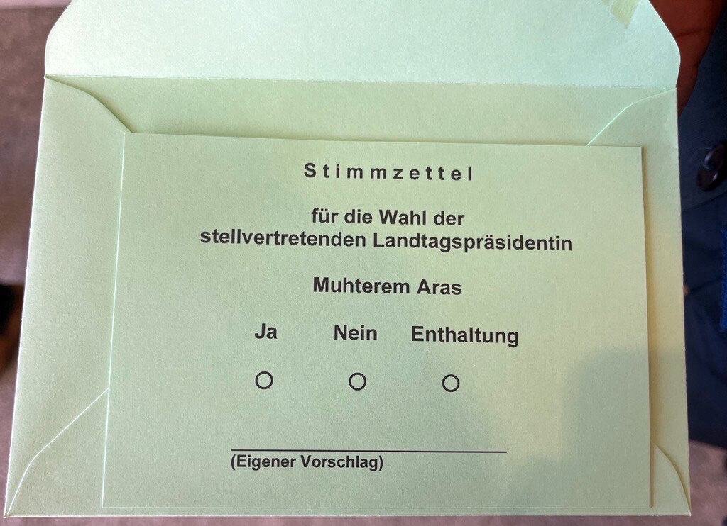 Grüner Stimmzettel mit Auswahl: Ja, Nein, Enthaltung. Name: Muhtarem Aras.