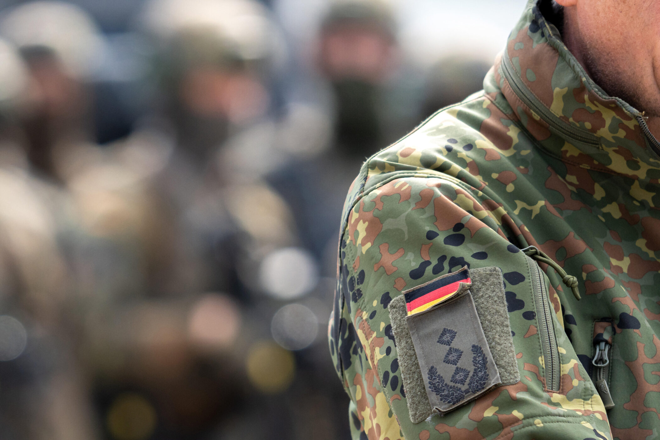 Camouflage-Jacke mit Abzeichen und schwarzer, roter, goldener Flagge.