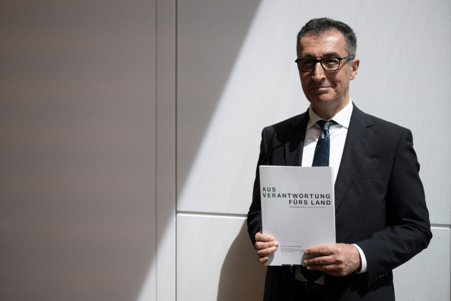 Ein Mann im Anzug hält ein Dokument mit dem Titel „AUS VERANTWORTUNG FÜRS LAND“.