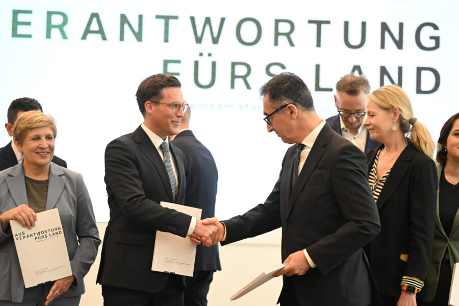 Sechs Personen, zwei Männer schütteln sich die Hand, Text: "Verantwortung fürs Land".