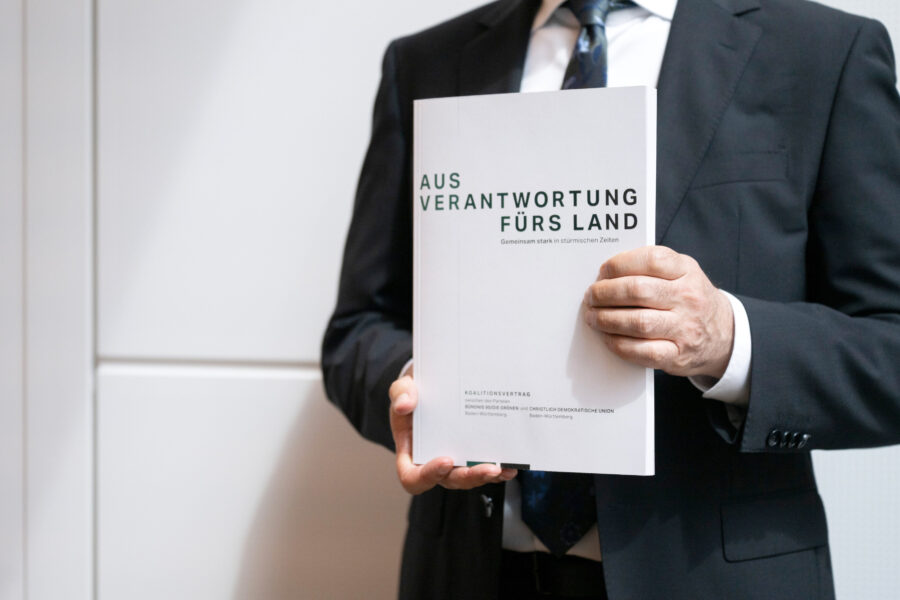 Person im Anzug hält Buch mit Titel "Aus Verantwortung fürs Land".