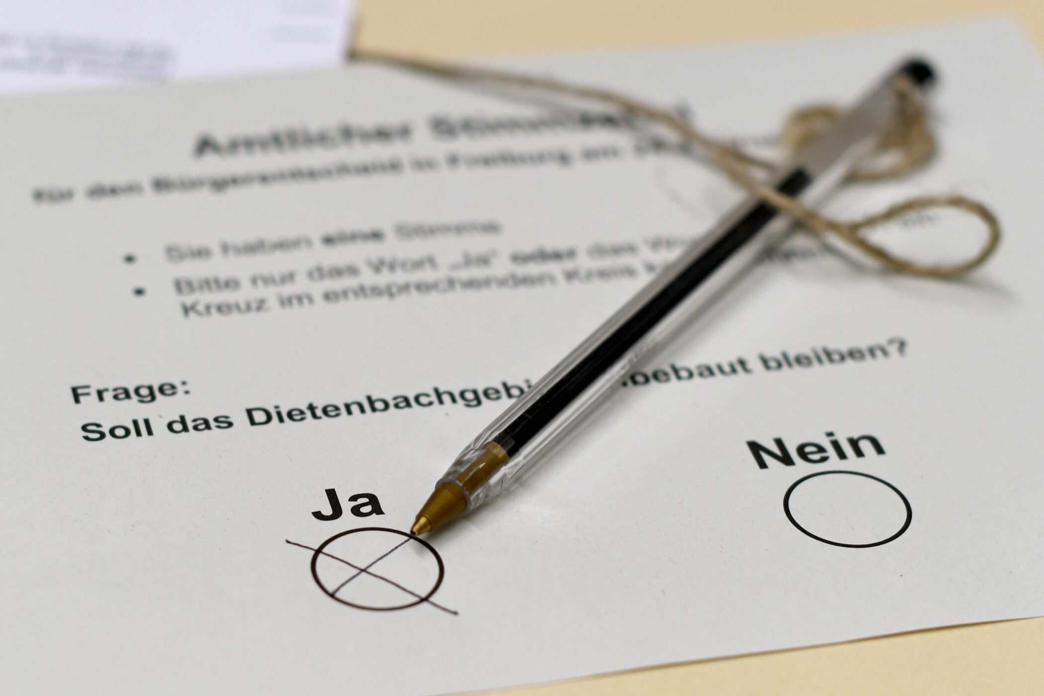 Stimmzettel mit Kreuz bei „Ja“, Stift auf weißem Papier.