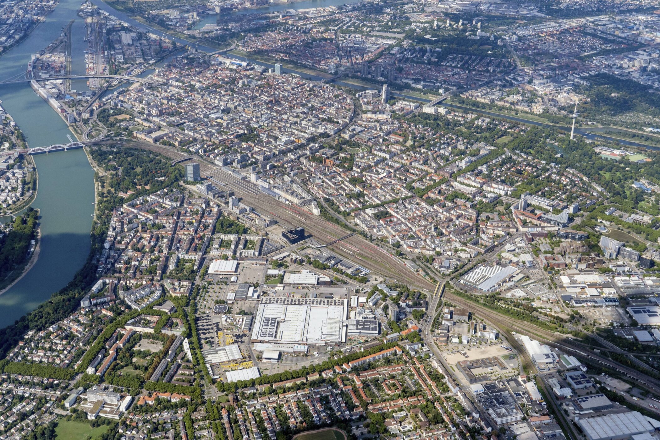 Luftaufnahme einer Stadt mit Fluss, Gebäuden, Straßen und Grünflächen.